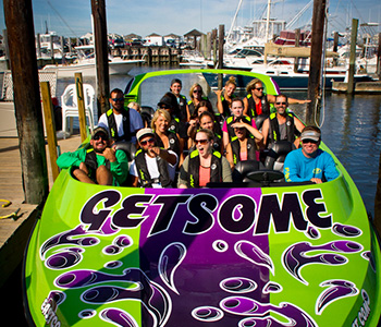 A group of people waving from a docked lime green jet boat