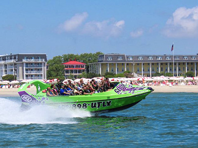 A group of people waving from a docked lime green jet boat